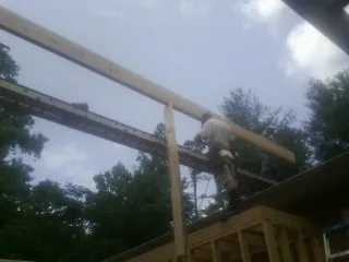 Carpenter setting a ridge beam over a new addition frame — Ice Dam Removal by Roofing Brothers in Seneca Falls