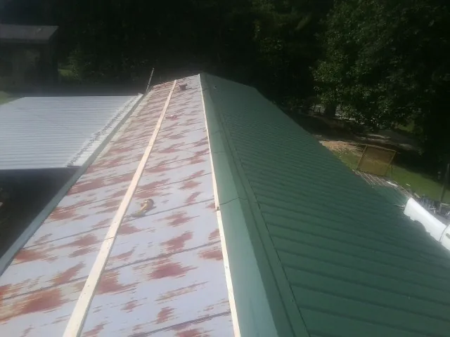 Old rusted panels beside newly installed green metal roofing — Wind Damage Roof Repair by Roofing Brothers in Seneca Falls