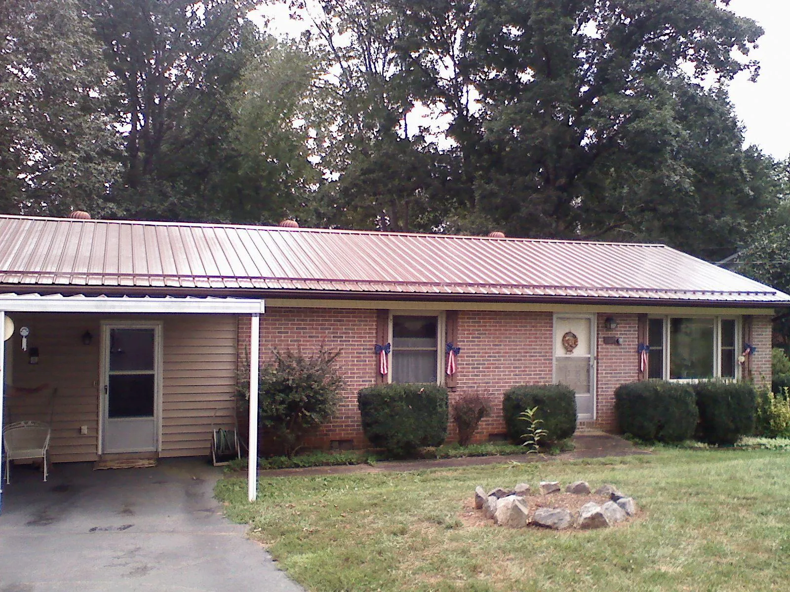 Bronze metal roof and carport on a brick ranch home — Roof Repair work by our crew in Seneca Falls